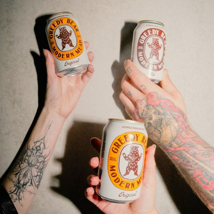 Tattooed hands holding cans of greedy bear
